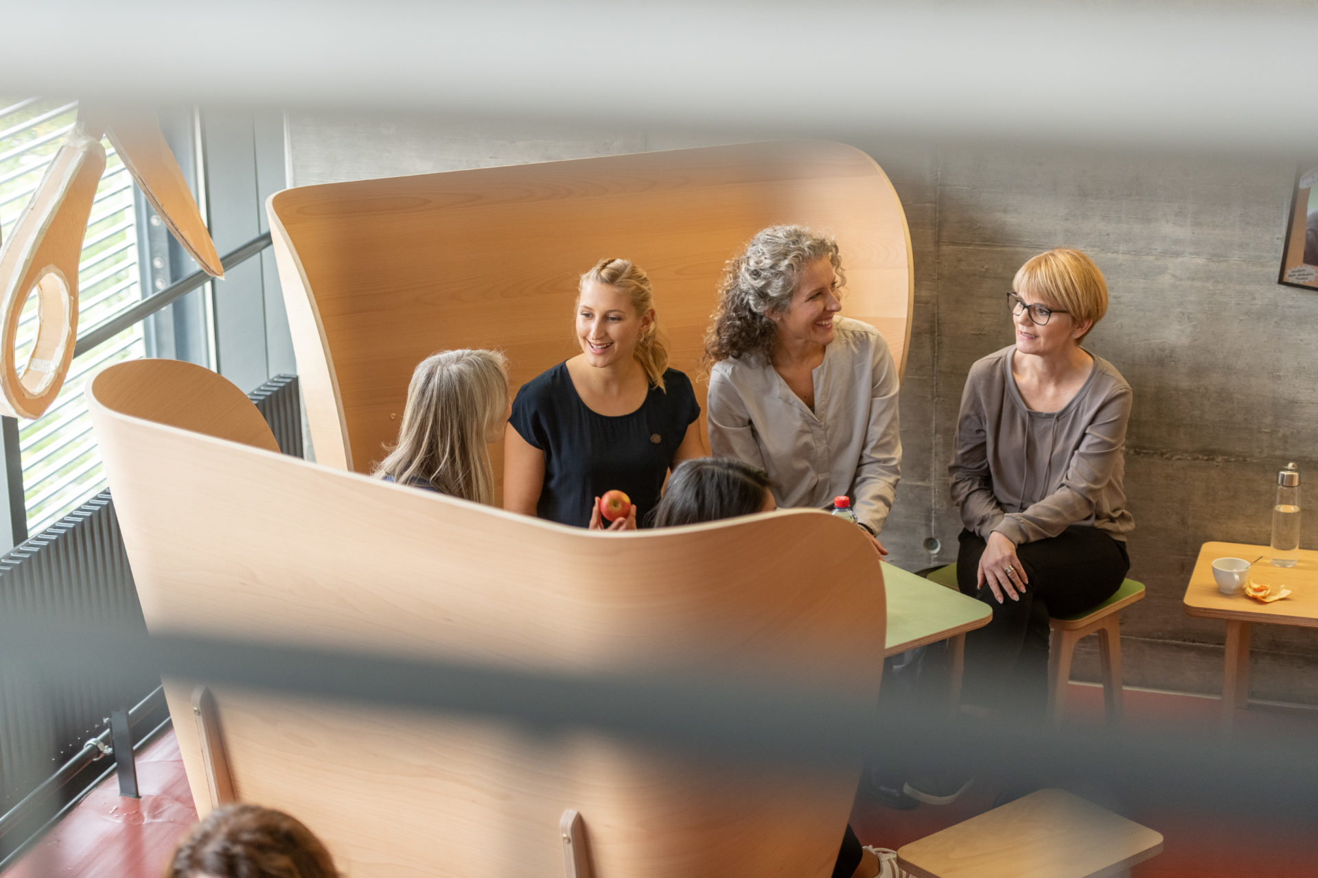 4 Kursteilnehmerinnen auf zwei Holzohrsessel und einen Stuhl verteilt diskutieren untereinander.